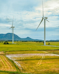 Panoramic view of wind farm or wind park, with high wind turbines for generation electricity with copy space on rice field, Ninh Thuan, Vietnam. Green energy concept.