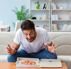Man eating pizza having a takeaway at home relaxing resting