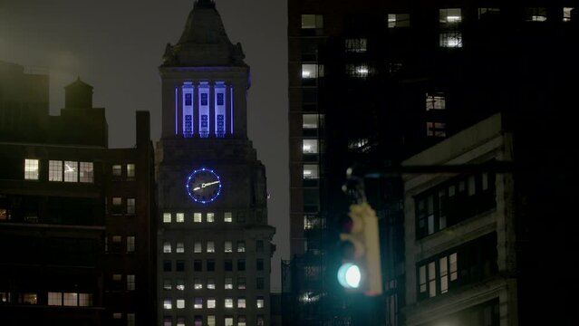 Manhattan Clock Tower with apartmnet buildings and red light in foreground, as seen from Astor Place at night