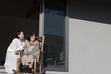 娘と母の高齢者介護の秋冬イメージ　仲良く会話する見上げる親子の広角...