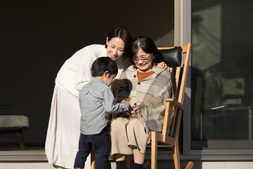 高齢者の親と子供　仲良く会話する娘と母と孫の介護のイメージ