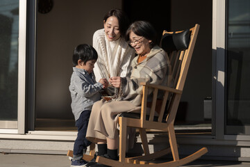 高齢者の親と子供　仲良く会話する娘と母と孫の介護のイメージ