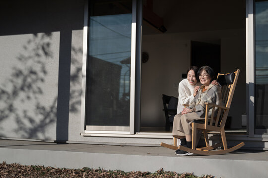 娘と母の高齢者介護の秋冬イメージ　仲良く会話する見上げる親子の広角 左にコピースペースあり