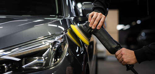 A master polishes the surface of a car body. 