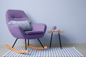 Rocking chair and table near lilac wall
