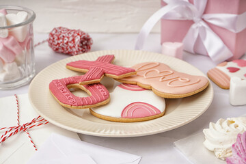 Plate with sweet cookies, marshmallows and envelopes on light table. Valentine's Day celebration