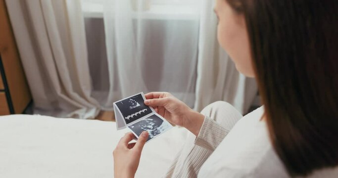 Miracle of pregnancy concept attractive woman touches her belly while scrolling through photos on her tablet, marveling at the amazing changes her body is undergoing.