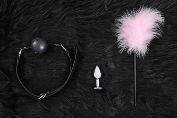 Sex toys on black fur blanket, top view