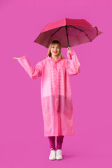 Young woman in pink raincoat with umbrella on purple background