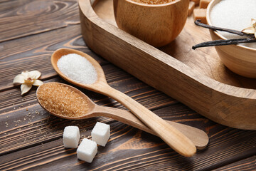 Spoons with aromatic vanilla sugar on wooden background