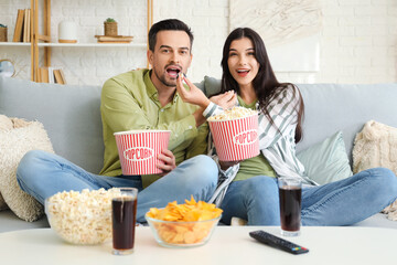 Young couple with popcorn watching TV at home
