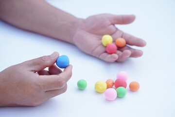 Close up man hands holds small colorful plasticine dough balls. Concept, alzheimer, weak muscle patients recovering activity by sculpting. Make concentration. Develop imagination.   