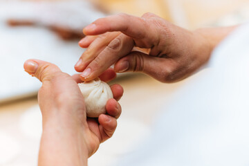 A chef's hands shaping pork bao in the kitchen