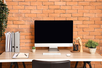 Blank computer monitor with folders on table in office