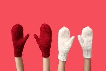 Hands in warm mittens on red background