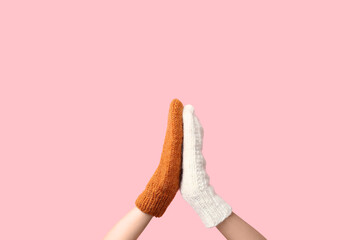 Hands in warm gloves giving high five to each other on pink background