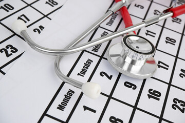 Medical examination concept, red stethoscope on calendar page.