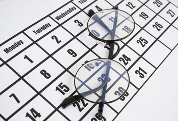 Black eyeglasses on calendar page close up. Planning business concept.