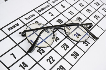 Eyeglasses on calendar page close up. 