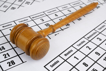 Judge's gavel on calendar pages close up. Legal proceeding concept.