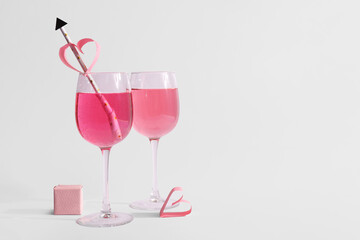 Glasses of tasty cocktail with straw and ring box on white background. Valentine's Day celebration