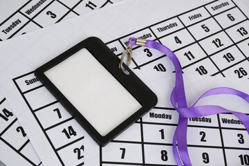 Accreditation concept. Blank black badge with purple string on calendar pages.