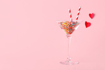 Glass of sweet candies with straws on pink background. Valentine's Day celebration