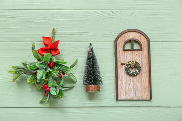 Fototapeta na wymiar Mistletoe branch with Christmas decorations on green wooden background