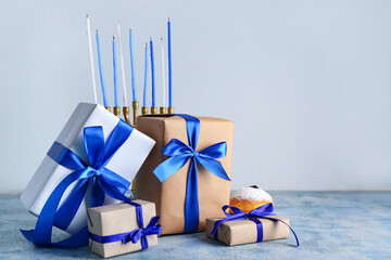 Gifts for Hanukkah celebration, donut and menorah on color background