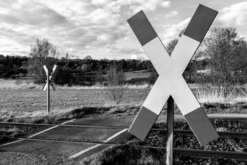 Railroad crossing with st. andrew's cross in the landscape in black and white