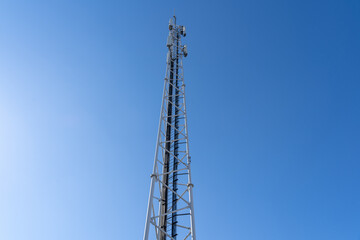Phone and internet tower with antennas in the blue sky