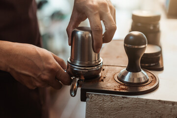 Closeup hand of barista preparation tampering ground coffee in portafilter for espresso machine....