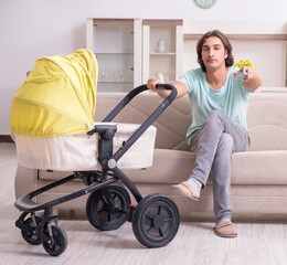 Young man looking after baby in pram