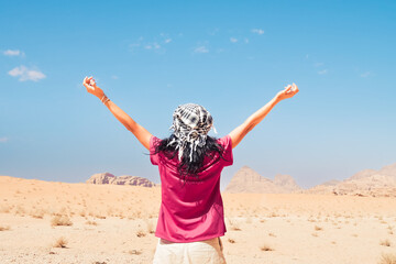 Happy joyful woman tourist stand with hands up on wadi rum desert on hike on holiday vacation in...