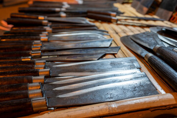 Pile of chopping knife on wooden table for sale at night market. - obrazy, fototapety, plakaty