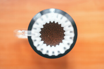 Drip coffee filter with hot water in glass dripper with ground coffee