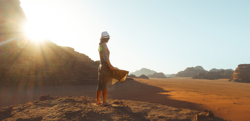 Close up woman tourist in dress stand on cliff barefoot at viewpoint enjoy sunrise on holiday vacation in beautiful Wadi rum desert, Jordan. Popular travel destination middle east