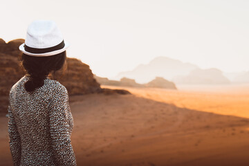 Woman tourist stand on cliff at viewpoint enjoy Wadi rum panorama on sunrise. Wadi Rum desert -...