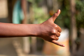 A man has one finger of his hand pointing forward and the thumb of the hand pointing up and blur...