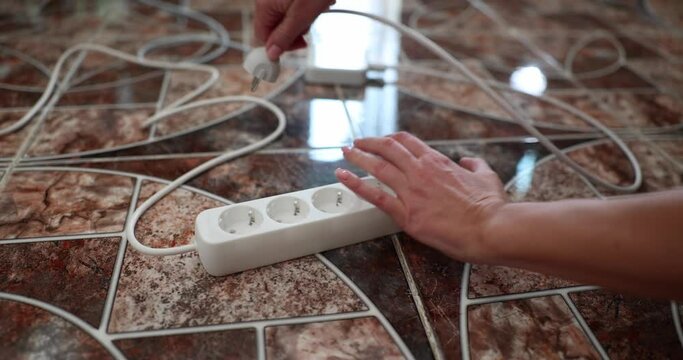 Woman hand taking out plug from electric socket with extension closeup 4k movie slow motion. Energy saving concept