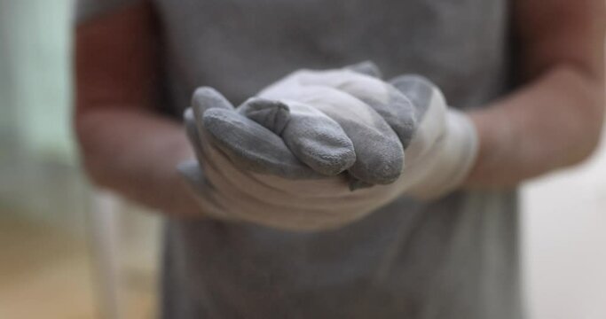 Builder in protective gloves clapping his hands from which dust flying closeup 4k movie slow motion. Finishing work laying plaster concept