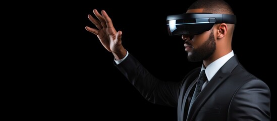 Businessman wearing virtual reality googles, pointing and touching invisible blank screen, black background, free space, mockup, viewed from behind.