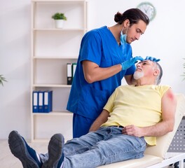 Injured old man visiting young male doctor traumatologist