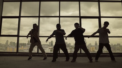 Silhouette shot of skilled choreographer group dancing together with sky scrapper, cityscape background. Young hipster team dancing performance. Sepia filter. Shadow. Outdoor sport 2024. Endeavor.