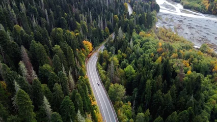 Cercles muraux Canada a road in the mountains in an autumn multicolored forest shot from above on a copter