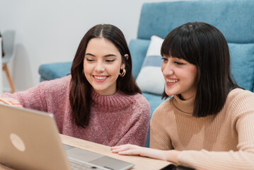 Smiling women browsing laptop together