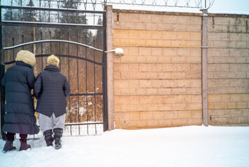 two females standing in front of the closed metal  gates, winter scene