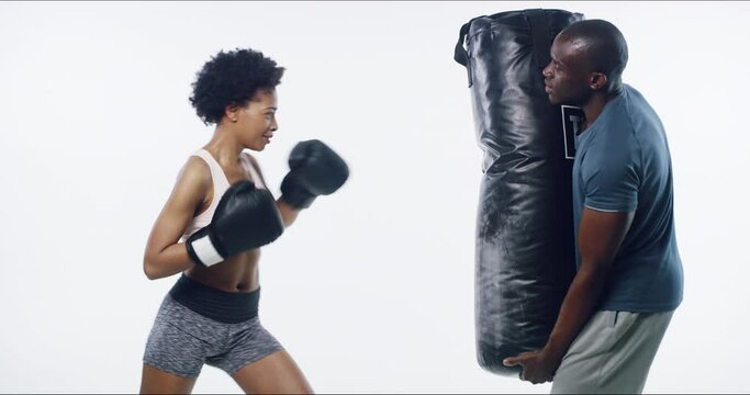 Boxer woman, coach and punching bag in studio for fitness, class and martial arts by white background. Girl, black man and personal trainer with mma, fight and boxing workout for wellness in profile