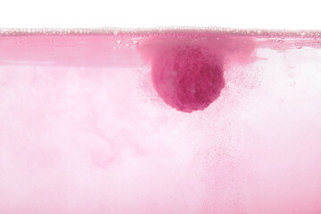 Pink bath bomb in water on white background