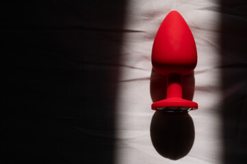 Red silicone anal plug on a white sheet. 